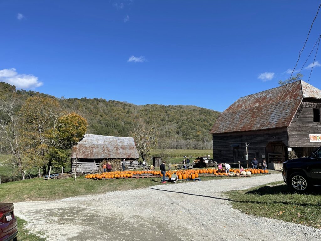 A Scenic Farm Featuring a Red Barn and a Parked Truck Under a Clear Blue Sky.